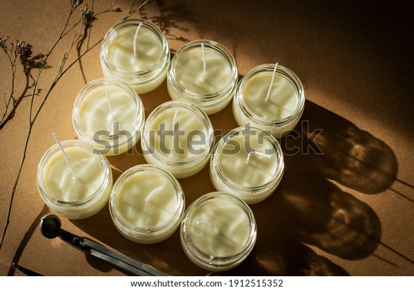 wooden wick candles. Handmade candle from\
paraffin and soy wax in glass with flowers and leaf on craft\
background. Let flay. Candle making. Top\
view.