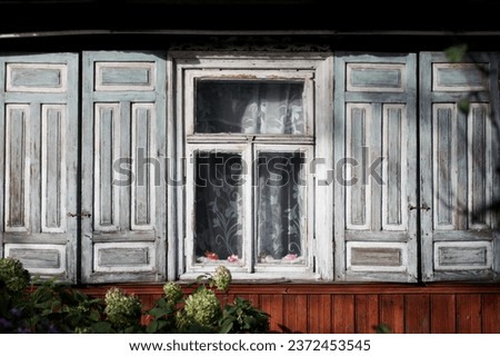 Wooden window background. Rustic cottage house wall. Vintage cabin white paint shutters. Countryside architecture texture. Rustic architecture. Village in eastern europe - Poland. Sunlight window.