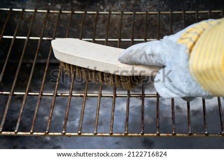 Wooden wire brush cleans dirty barbecue grill rust. Leather protection gloves.