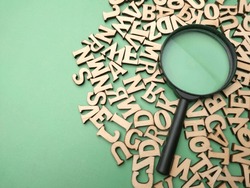 Wooden Word And Magnifying Glass On A Green Background. Business Concept.