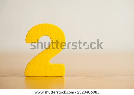 Wooden yellow number 2 (two) sign stand on wooden table white background with copy space. Number two 2nd in business ranking, marketing, education grade, sport second runner up and competition concept