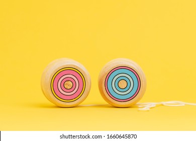 Wooden yoyo or yo-yo toy on solid yellow background with copy space using as volatility and risk in price of investment asset or yoyo effect when try to losing weight concept.