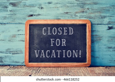 A Wooden-framed Chalkboard With The Text Closed For Vacation Written In It, On A Rustic Wooden Surface, Against A Blue Wooden Background