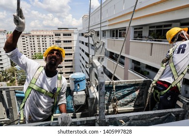 Woodlands / Singapore - May 24th 2019: A painter is painting the wall from his gondola.