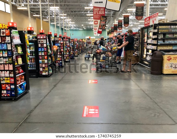 Woodlands, TX / USA - May 14th 2020: As social\
distancing becomes our new normal people are rising to the\
challenge. Photo of people in line and wearing masks at the\
Woodlands, Texas HEB grocery\
store