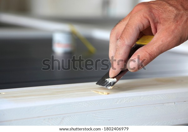 woodwork. Putty knife in man\'s hand. DIY worker\
applying filler to the wood. Removing holes from a wood surface.\
Preparation of wood  before impregnation with varnish. Application\
of putty. Copy space