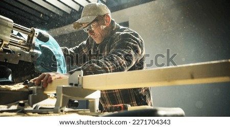 Woodworker General Construction Contractor Behind Powerful Wood Saw. Cutting Beams to Size. Panoramic Photo.