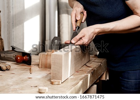 In the woodworkers shop. Making handmade wooden furniture and  manufacture. A joiner processes a workpiece with a chisel.