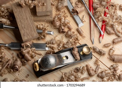 Woodworking accessories, red carpentry pencil, wood shavings. Carpenter cabinet maker hand tools on the workbench.