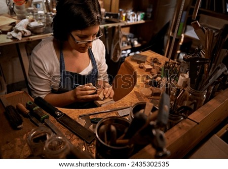 Woodworking, tools and artist in workshop with creative project or sculpture on table at night. Artisan, carpenter and woman with talent for creativity in dark studio in process of carving wood