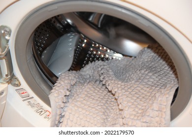 A Wool Blanket In The Open Door Of The Washing Machine