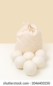 Wool Dryer Balls In Cotton Bag On Beige Background. Eco Friendly Laundry Supplies. Alternative Drying Of Linen. Still Life. Vertical Size