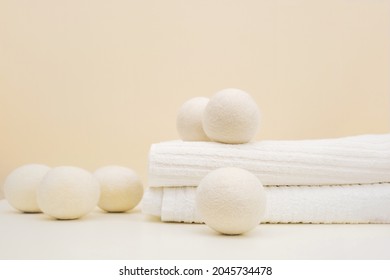 Wool Dryer Balls On White Towel On Beige Background. Eco Friendly Laundry Supplies. Alternative Drying Of Linen. Still Life. Text Space