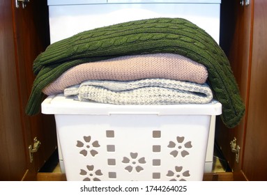 Woolen Items Are Lying On A White Laundry Basket Waiting To Be Washed