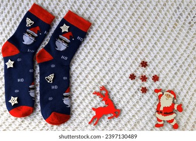 Woolen socks with Christmas pattern, Santa Claus, Saint Nicholas, and New Year s decorations lie on white background. Christmas and New Year holidays concept, gifts background