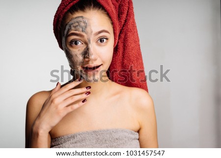 A woolly surprised girl with a towel on her head applied a useful mask to half the face, spa procedures