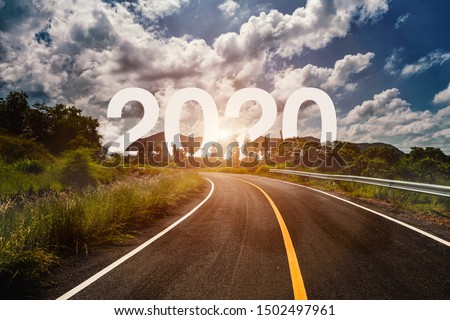 The word 2020 behind the tree of empty asphalt road at golden sunset and beautiful blue sky. Concept for vision year 2020. 