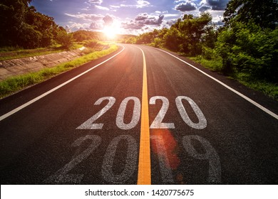 La palabra 2020 escrita en carretera en medio de la ruta de asfalto vacío al atardecer dorado y hermoso cielo azul. Concepto para el nuevo año 2020.