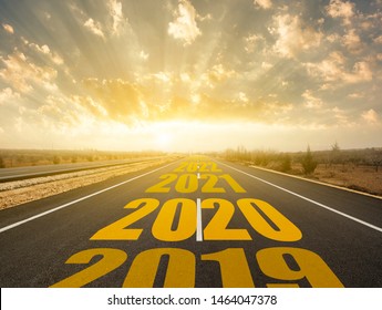 The Word 2020 Written On Highway Road In The Middle Of Empty Asphalt Road At Golden Sunrise