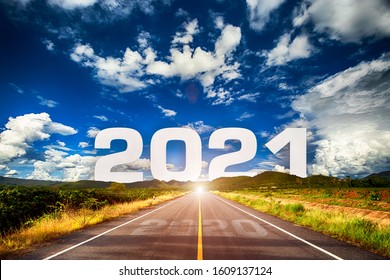 The word 2021 behind the mountain of empty asphalt road at golden sunset and beautiful blue sky. Concept for vision year 2021. 
