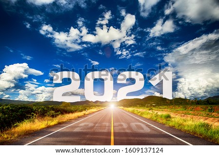 The word 2021 behind the mountain of empty asphalt road at golden sunset and beautiful blue sky. Concept for vision year 2021. 