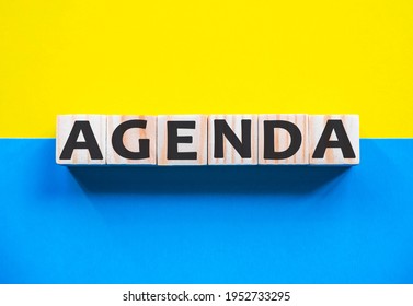 Word Agenda On Wooden Cubes With Word On Beautiful Yellow And Blue Background. Business, Media Marketing Concept. List Of Items To Be Discussed At Formal Meeting