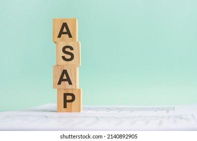 word ASAP with wood building blocks, light gray background. document with numbers on background, business concept. space for text in right. front view. ASAP - AS SOON AS POSSIBLE