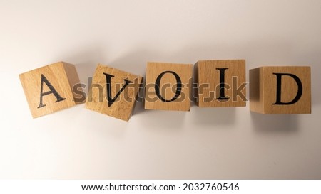 The word AVOID was created from wooden cubes. Consumption and shopping. Close-up.