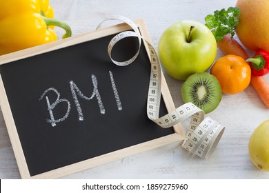 Word BMI On Chalkboard. Fruits, Vegetables And Measuring Tape, Healthy Diet Concept 