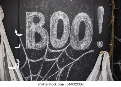 Word Boo Drawn With White Crayon On Black Drawing Board Decorated With Paper Handmade Bats And Web. Decor Of Photobooth For Halloween Party. Vertical Color Photo.