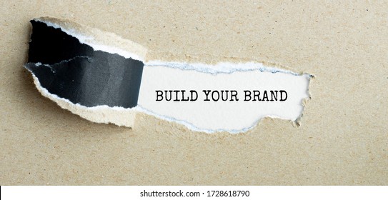 The Word BUILD YOUR BRAND Appearing Behind Torn Brown Paper.