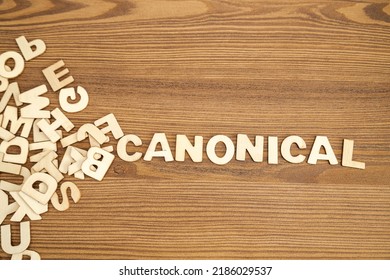 Word CANONICAL written with solid letters on a board. Wooden letters on wooden background.