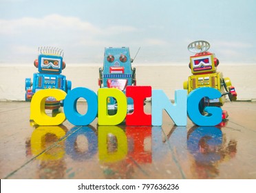the word coding wit wooden letters on a old wooden floor with retro robot toys