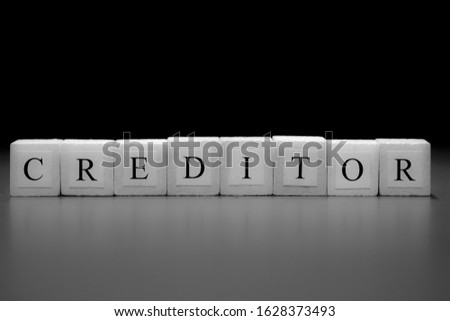 The word CREDITOR written on wooden cubes isolated on a black background...