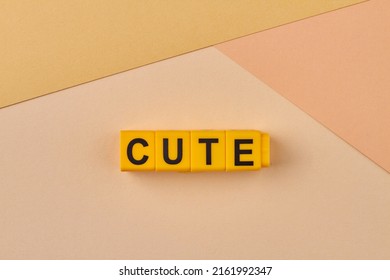 Word cute written on yellow blocks against color background. Attractive in a pretty or endearing way.