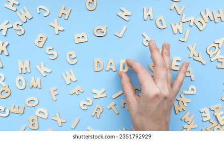 The word dad is made up of letters. Pile of wooden block letters over the blue background - Powered by Shutterstock