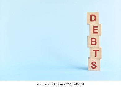 Word debts in wooden blocks. Growing financial debt, pile up, accumulation, stockpile and increase concept.