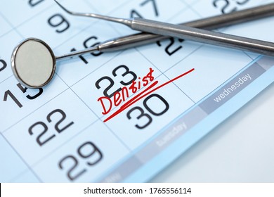The word Dentist on the calendar and dental instruments close-up. Dental health and teeth care concept.