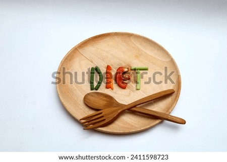 the word diet on a wooden plate made of sliced ​​vegetables such as tomatoes, long beans, mustard greens isolated on a white background.