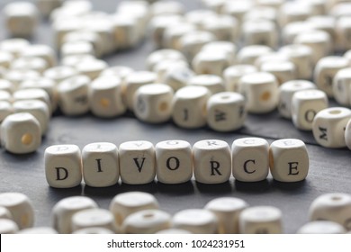 Word - Divorce made up of wooden letters on the table with wedding rings.