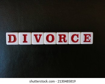 The word Divorce is spelled with white and red tiles on a black leather background sheet