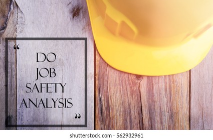 Word DO JOB SAFETY ANALYSIS With Yellow Safety Helmet On Wooden Base