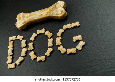 The Word Dog With Little Dog Treats And A Big Bone On Black Background