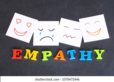 Word Empathy made of colorful letters and funny faces drawn on notes on the dark background. 