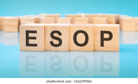 word ESOP on wooden cubes on blue background. the inscription on the cubes is reflected from the surface. business concept