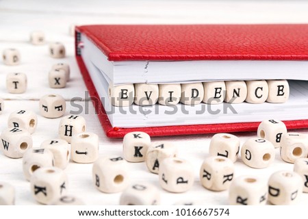 Word Evidence written in wooden blocks in red notebook on white wooden table. 