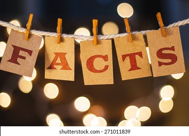 The Word FACTS Printed On Clothespin Clipped Cards In Front Of Defocused Glowing Lights.