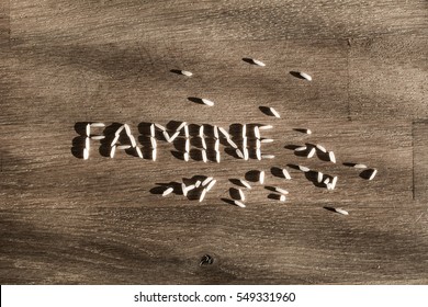 Word famine made of few white rice grains on wooden table - symbol of hunger and scarcity of food.