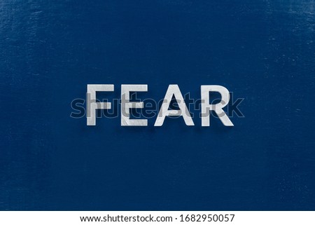 the word fear laid with silver letters on blue color surface