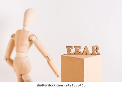 The word fear and a wooden sad man stands with his back - Powered by Shutterstock